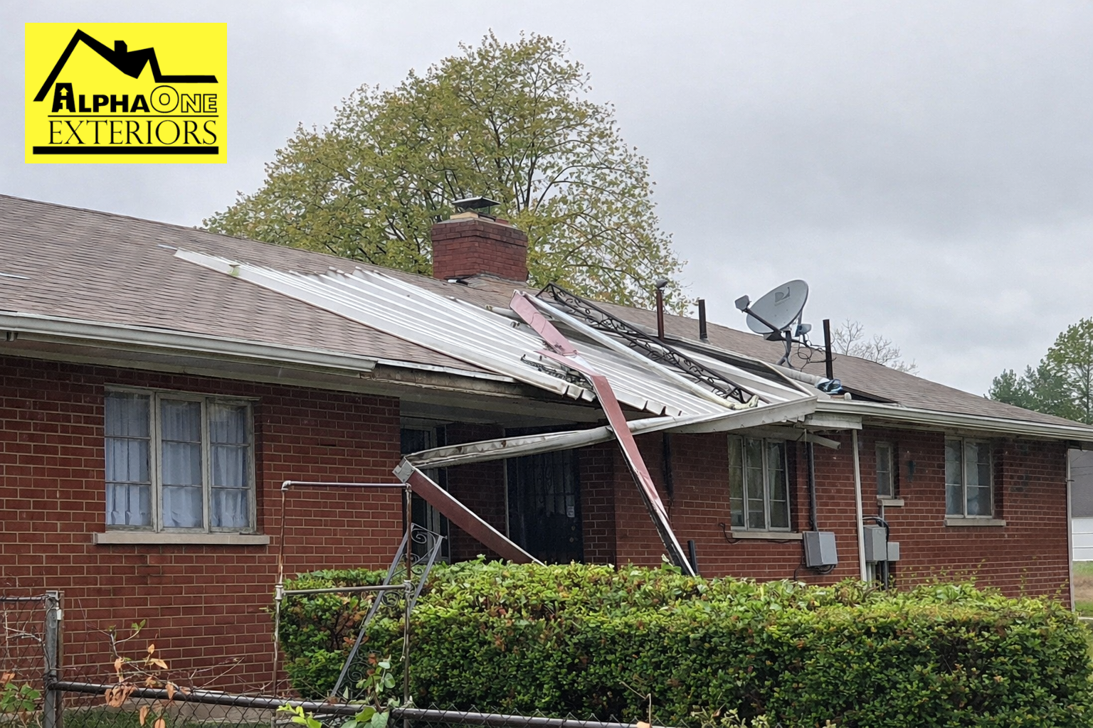 Storm damaged home in Dayton, Ohio with collapsed metal porch roof and structural damage after severe wind event.
