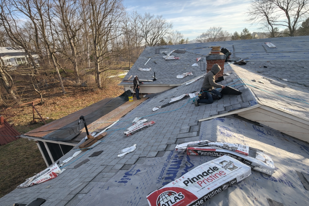 Roofing crew installing Atlas Pinnacle Pristine shingles on residential home in Kettering Ohio during full roof replacement with synthetic underlayment visible