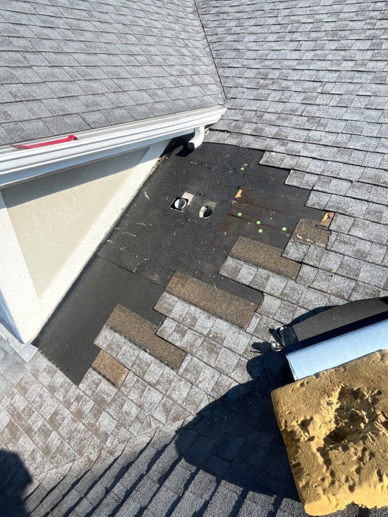 Roof repair in progress replacing damaged flashing and shingles near wall transition in Dayton, Ohio
