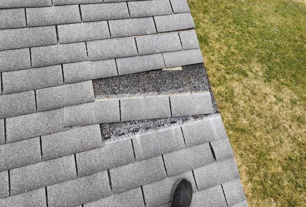 Wind-damaged asphalt shingles lifted and creased on a residential roof in Dayton, Ohio