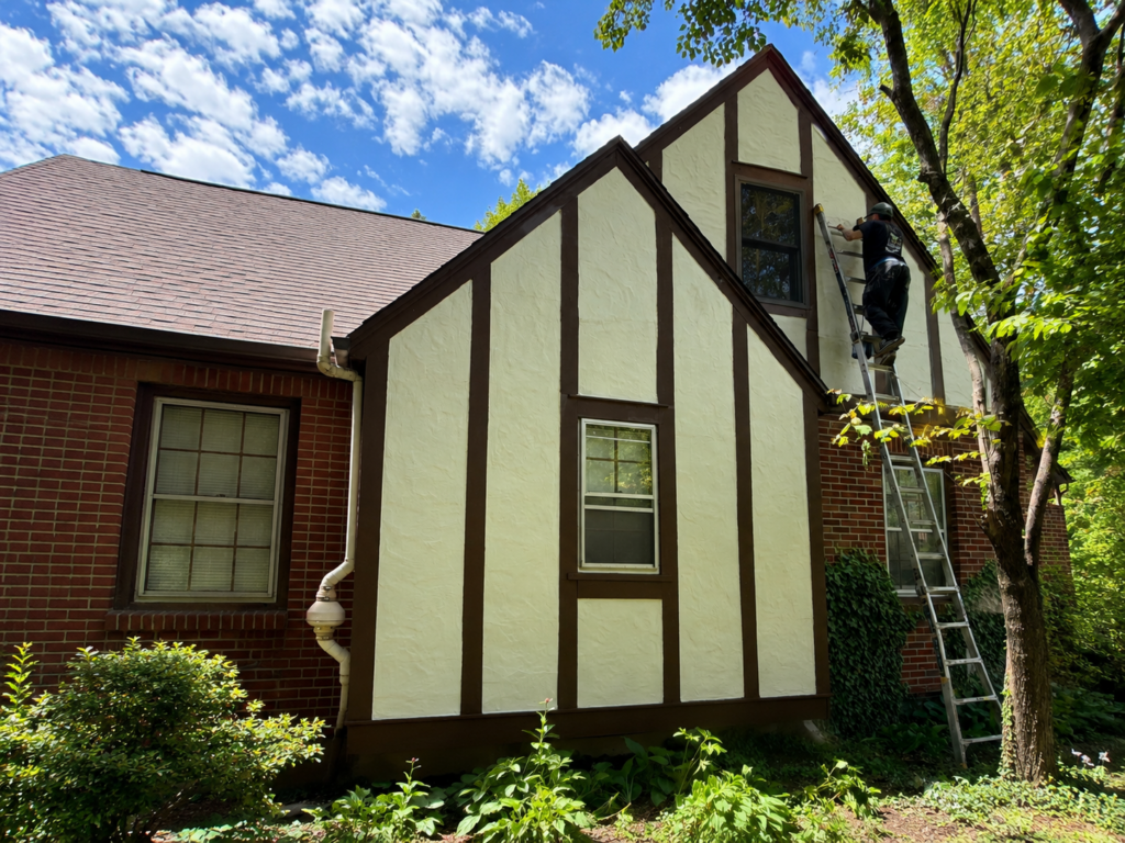 Exterior painting contractor in Centerville Ohio painting Tudor style home siding and trim with ladder setup beside house