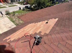 Roof repair in Dayton Ohio showing new asphalt shingles installed to replace damaged sections with visible color difference during transition
