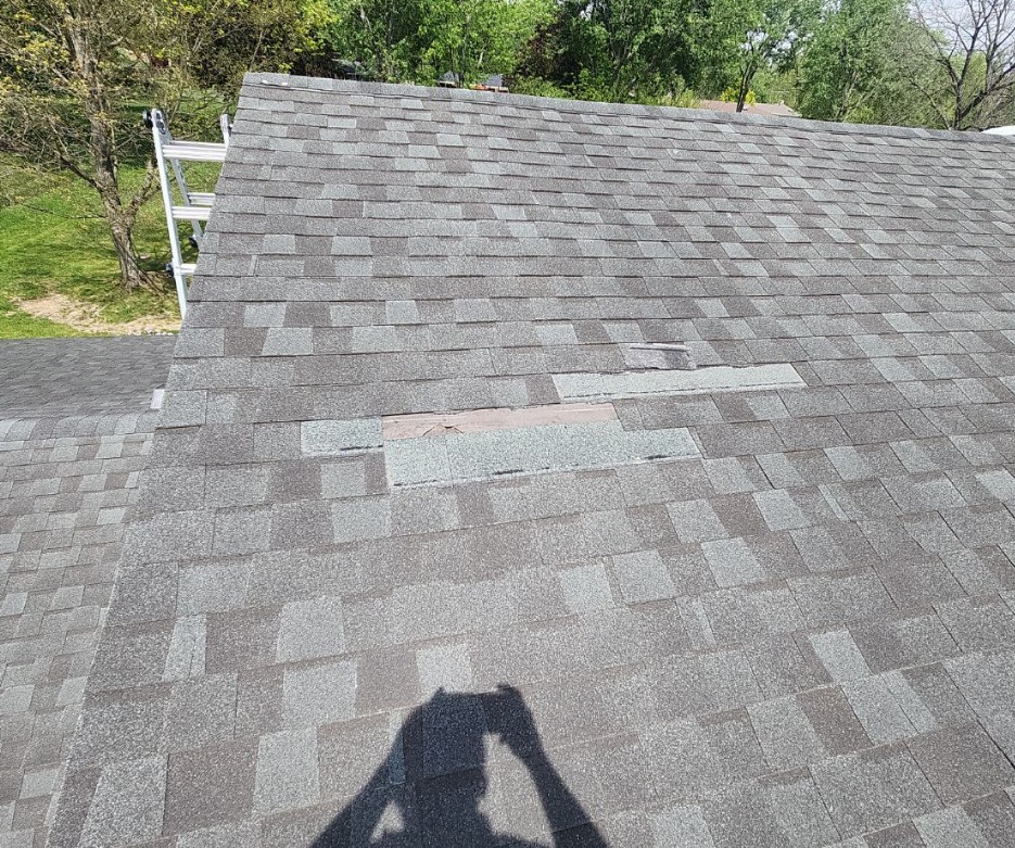 Wind damaged asphalt shingles on residential roof in Beavercreek Ohio showing lifted and missing shingles after storm