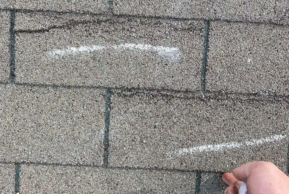 Wind-creased asphalt shingles showing storm damage on a residential roof in Dayton, Ohio