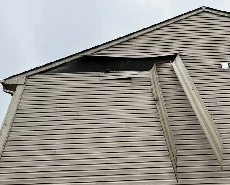 Wind damaged vinyl siding pulled loose on a home in Springboro, Ohio