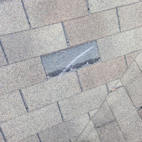 Wind-damaged asphalt shingle lifted on residential roof in Dayton, Ohio