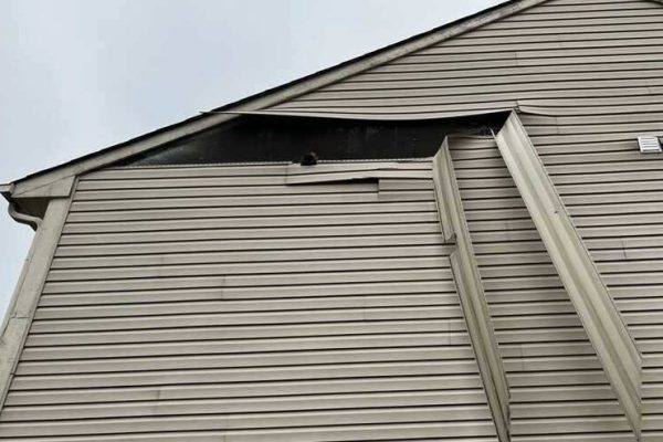 Wind-damaged vinyl siding pulled loose from a residential home in Springboro, Ohio